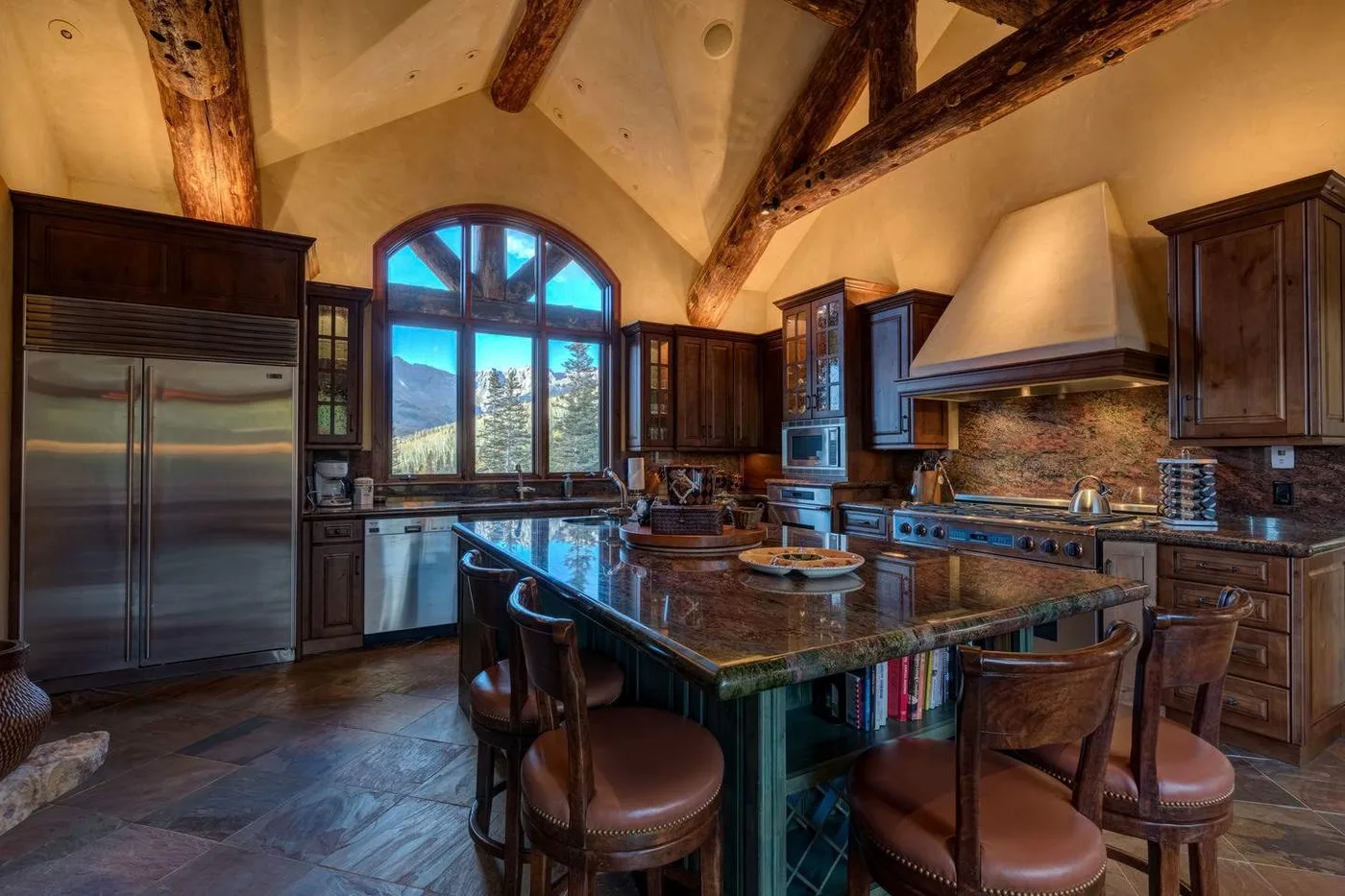 A spacious kitchen with dark cabinetry, a central island, and exposed wooden beams.