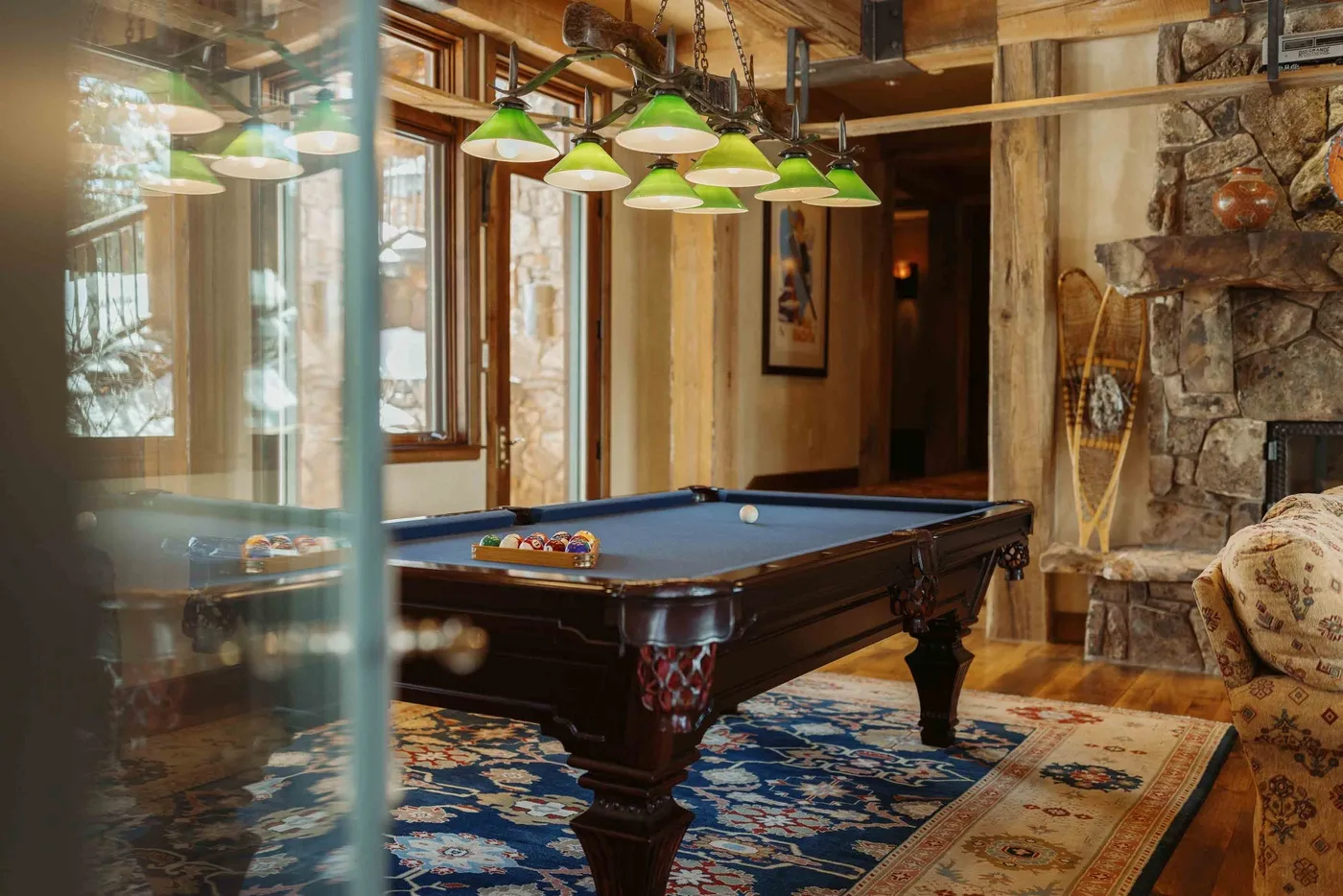 A game room with a billiards table beneath green pendant lights.