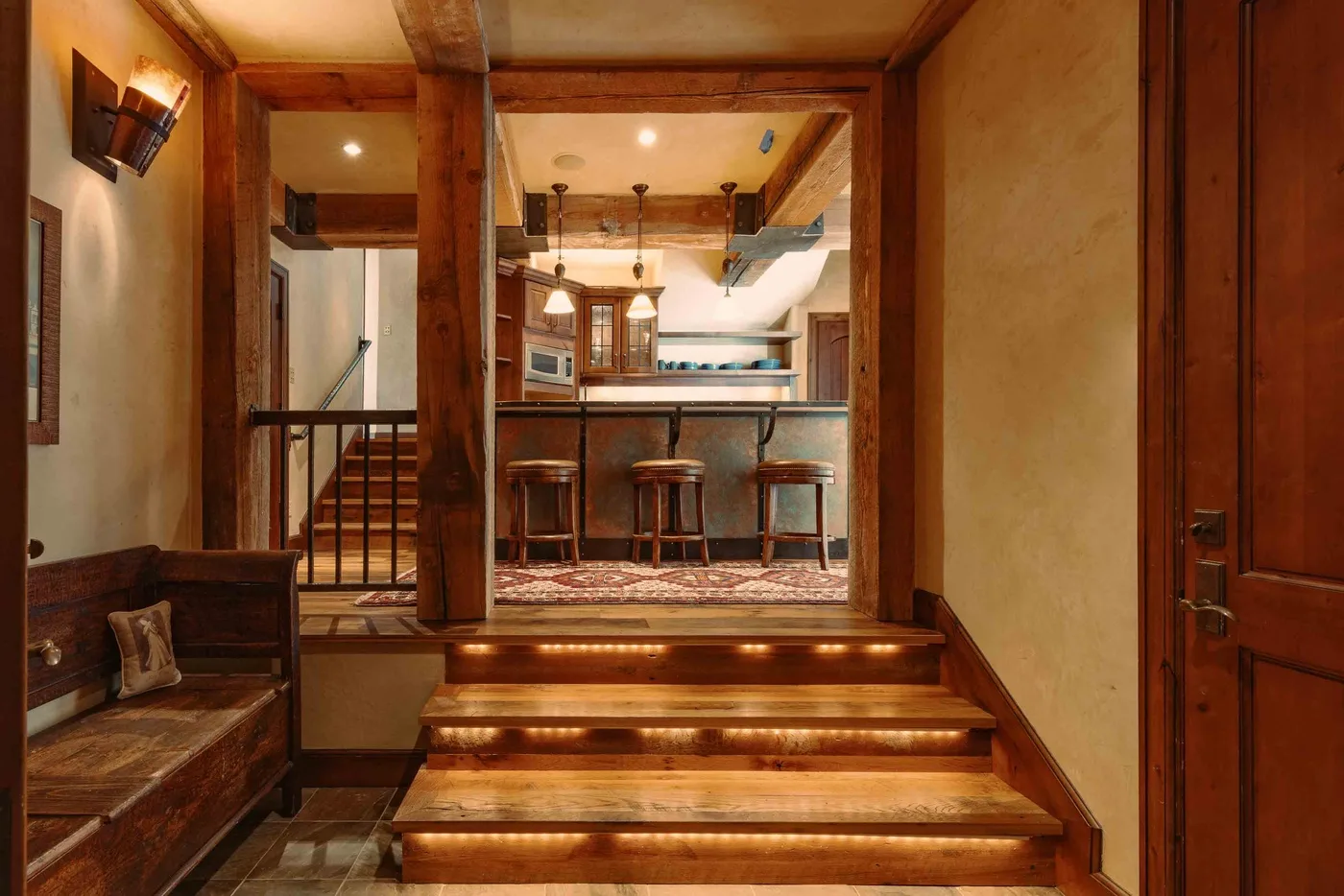 A warmly lit interior with wooden steps leading up to a bar counter and seating.