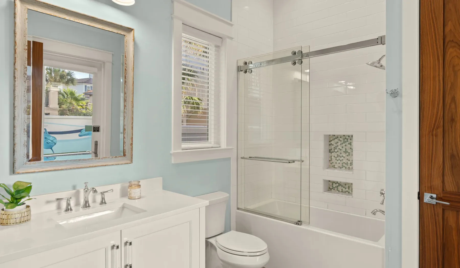 Un baño luminoso con lavabo, espejo y ducha de cristal.