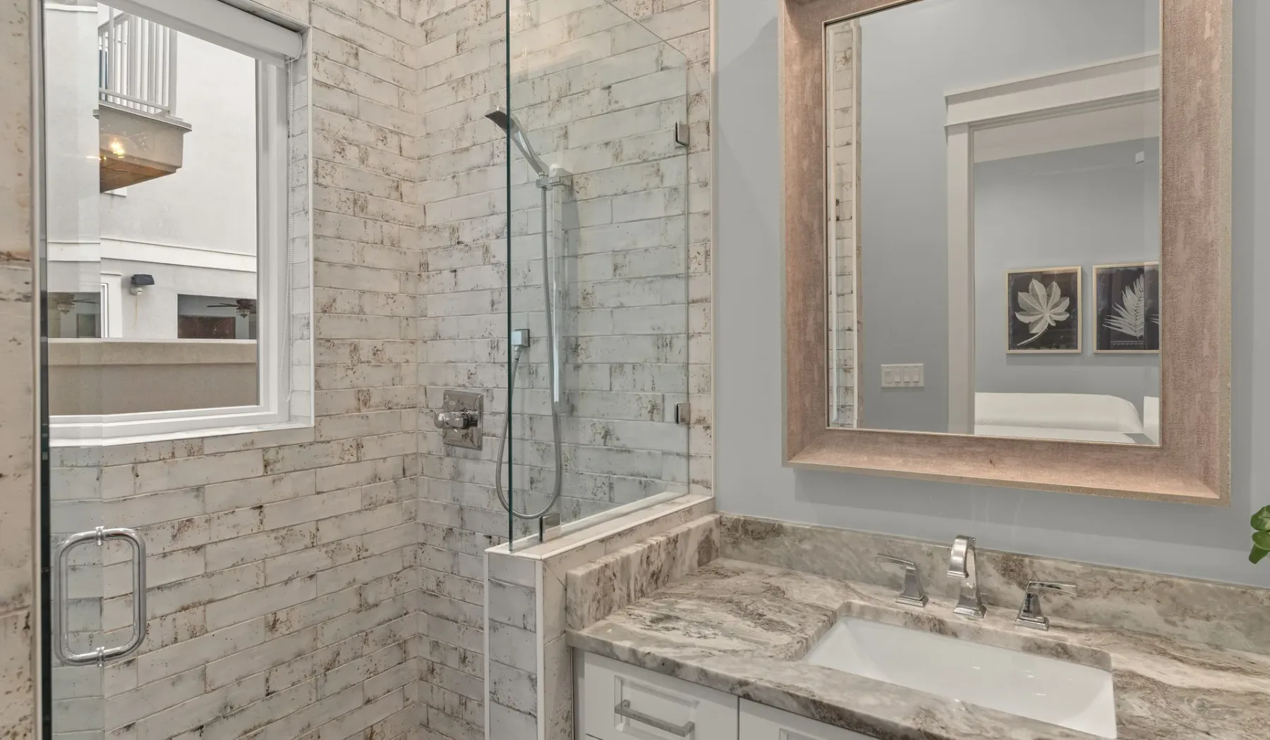 Un baño con una ducha de vidrio y un lavabo bajo un espejo grande.