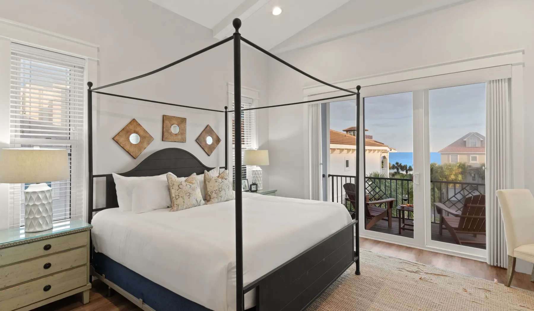 Un dormitorio luminoso con una cama con dosel y puertas de vidrio que dan a un balcón.