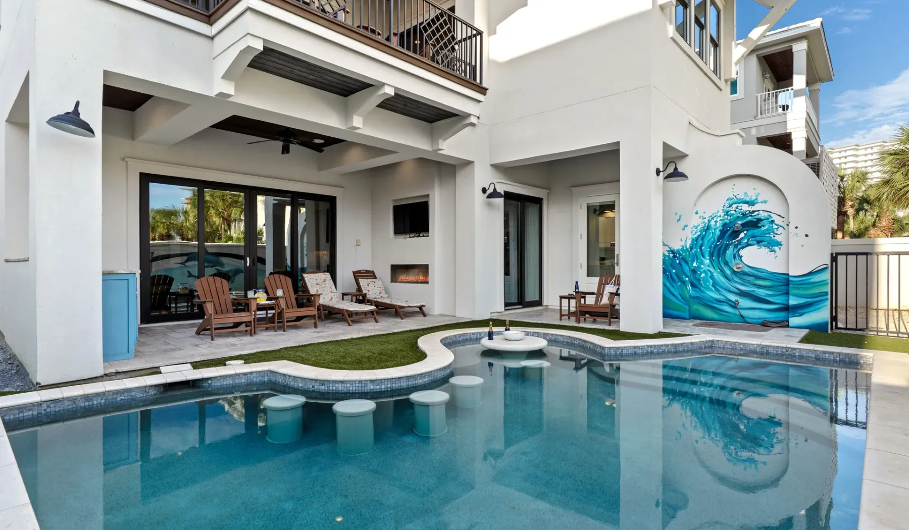 Una piscina en un patio junto a un edificio blanco con un mural de olas azules.