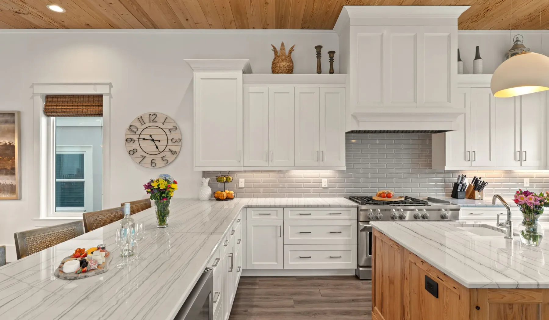 Una cocina luminosa con gabinetes blancos, una estufa central y encimeras con vetas.