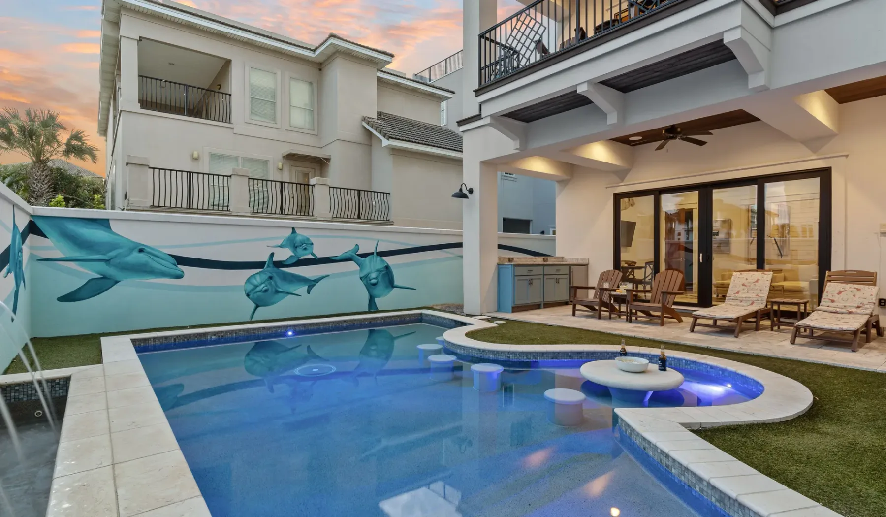 Una piscina exterior está junto a un muro con un mural y un patio cubierto con asientos.