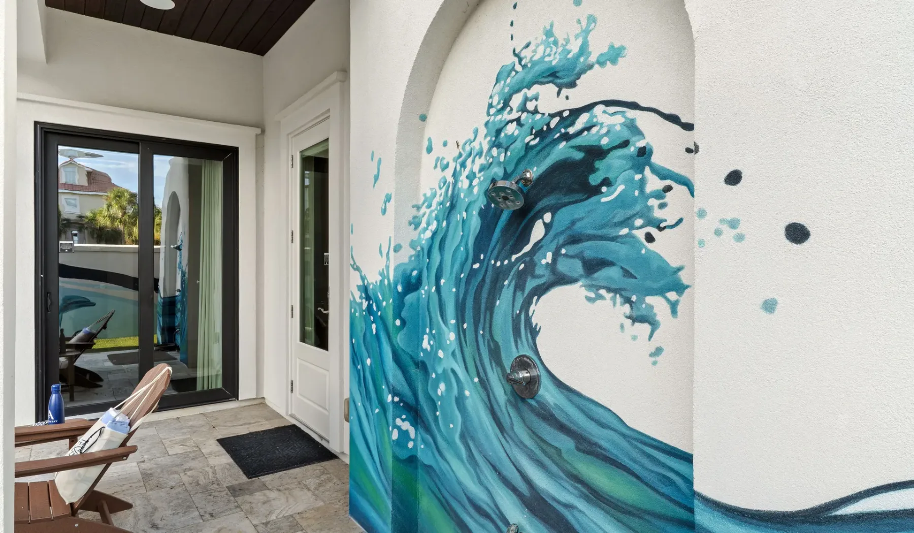 Una entrada con un gran mural azul de una ola junto a una puerta de vidrio.