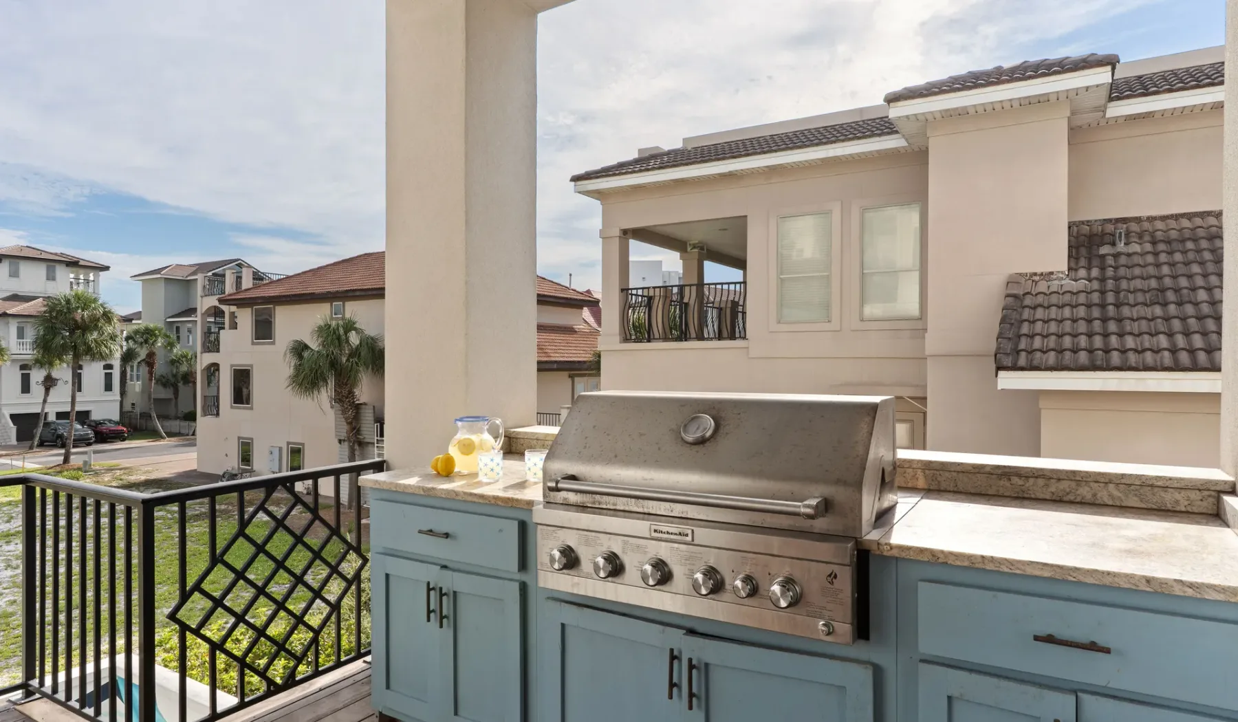 Una cocina exterior en un balcón con una parrilla de acero inoxidable y edificios vecinos a la vista.