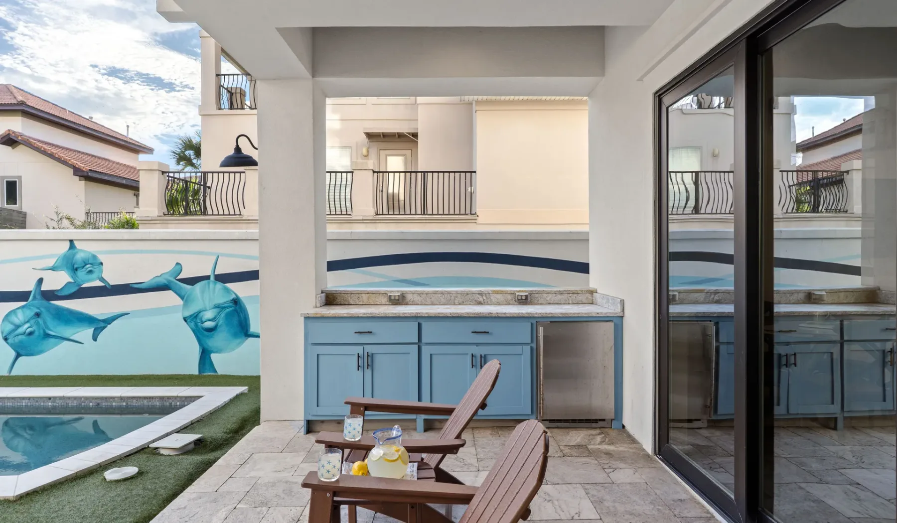 Un patio junto a la piscina, con muebles azules y sillas junto al agua.
