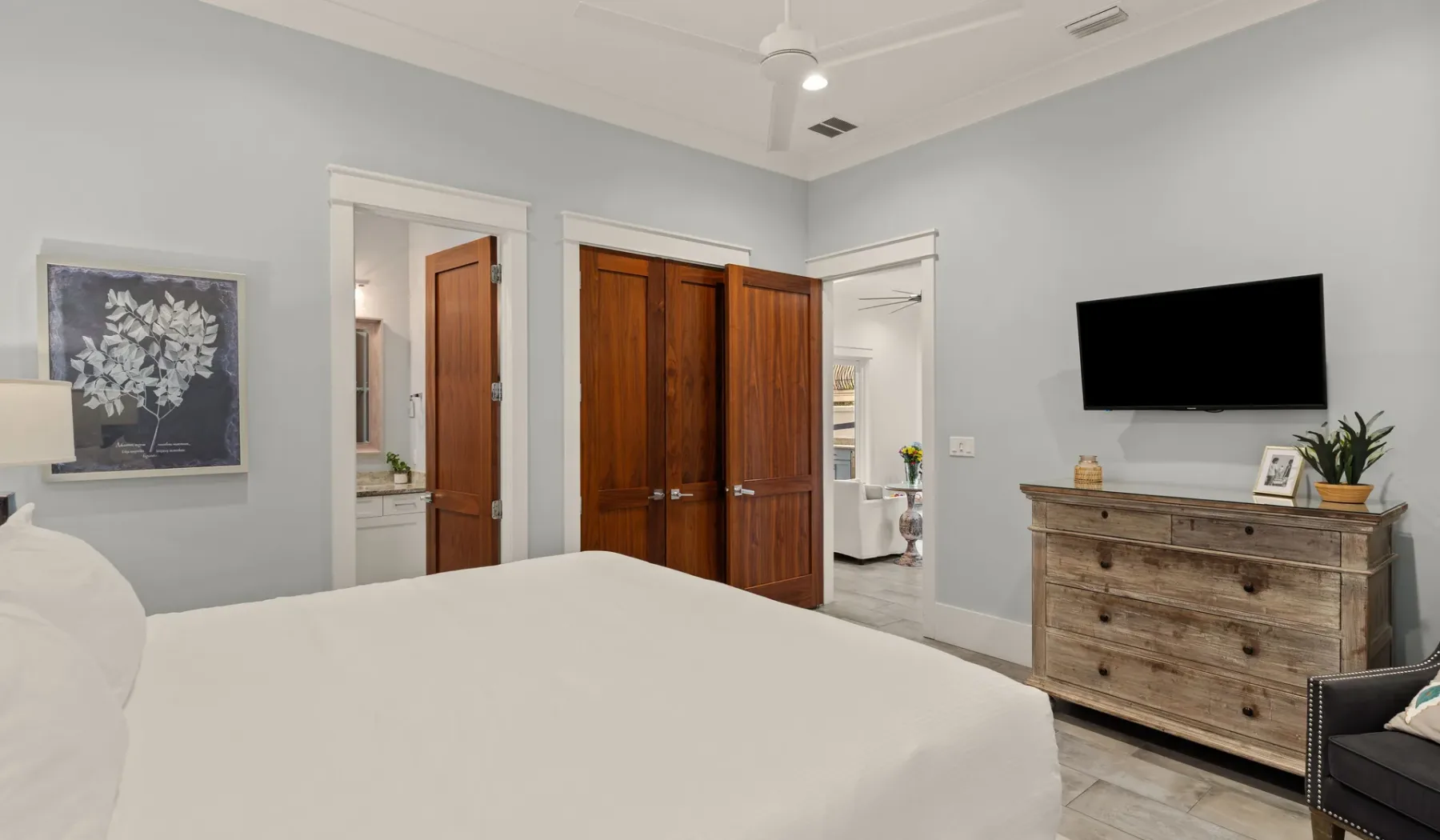 Un dormitorio con una cama, un armario de madera y un televisor sobre una cómoda.