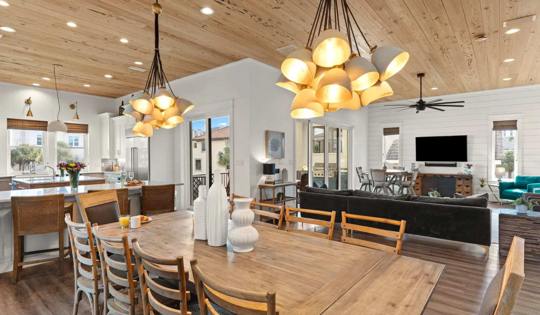 Comedor y sala de estar de planta abierta con una gran mesa de madera y lámparas colgantes.