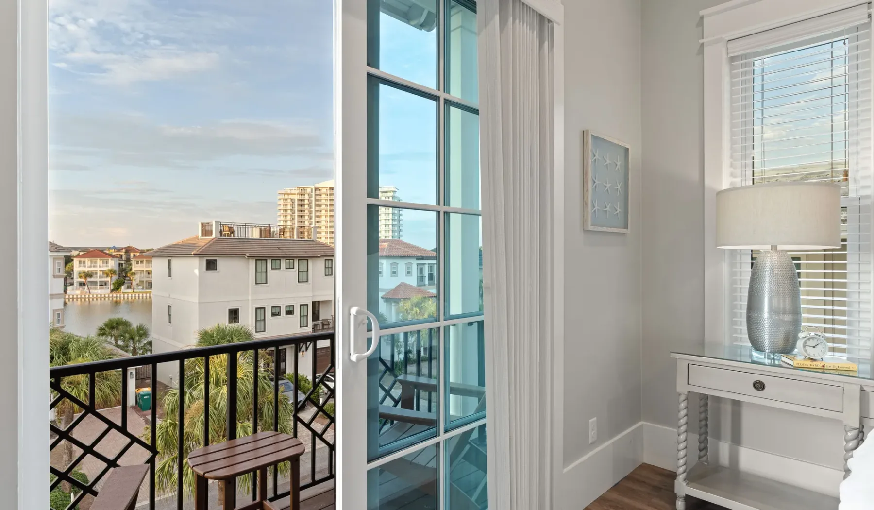 Una habitación luminosa da a un balcón con una mesa pequeña y vistas al agua.