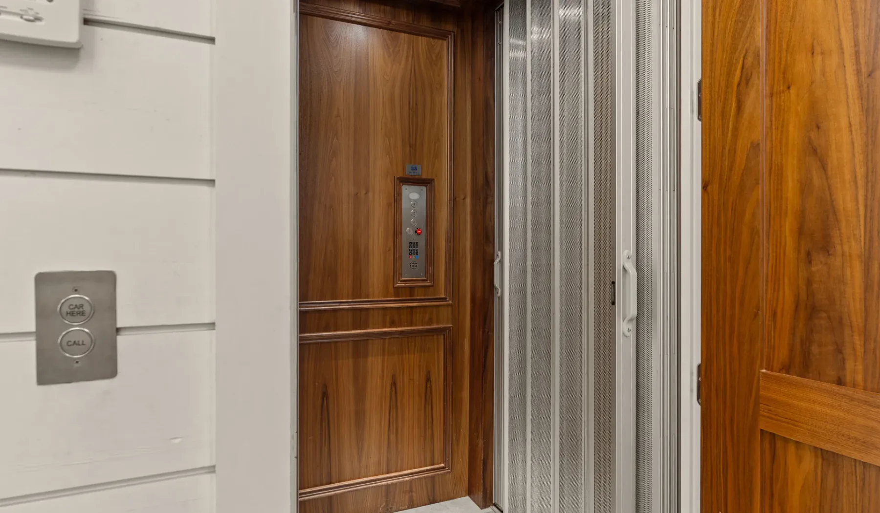 La entrada de un ascensor con puertas de madera y botones de llamada.