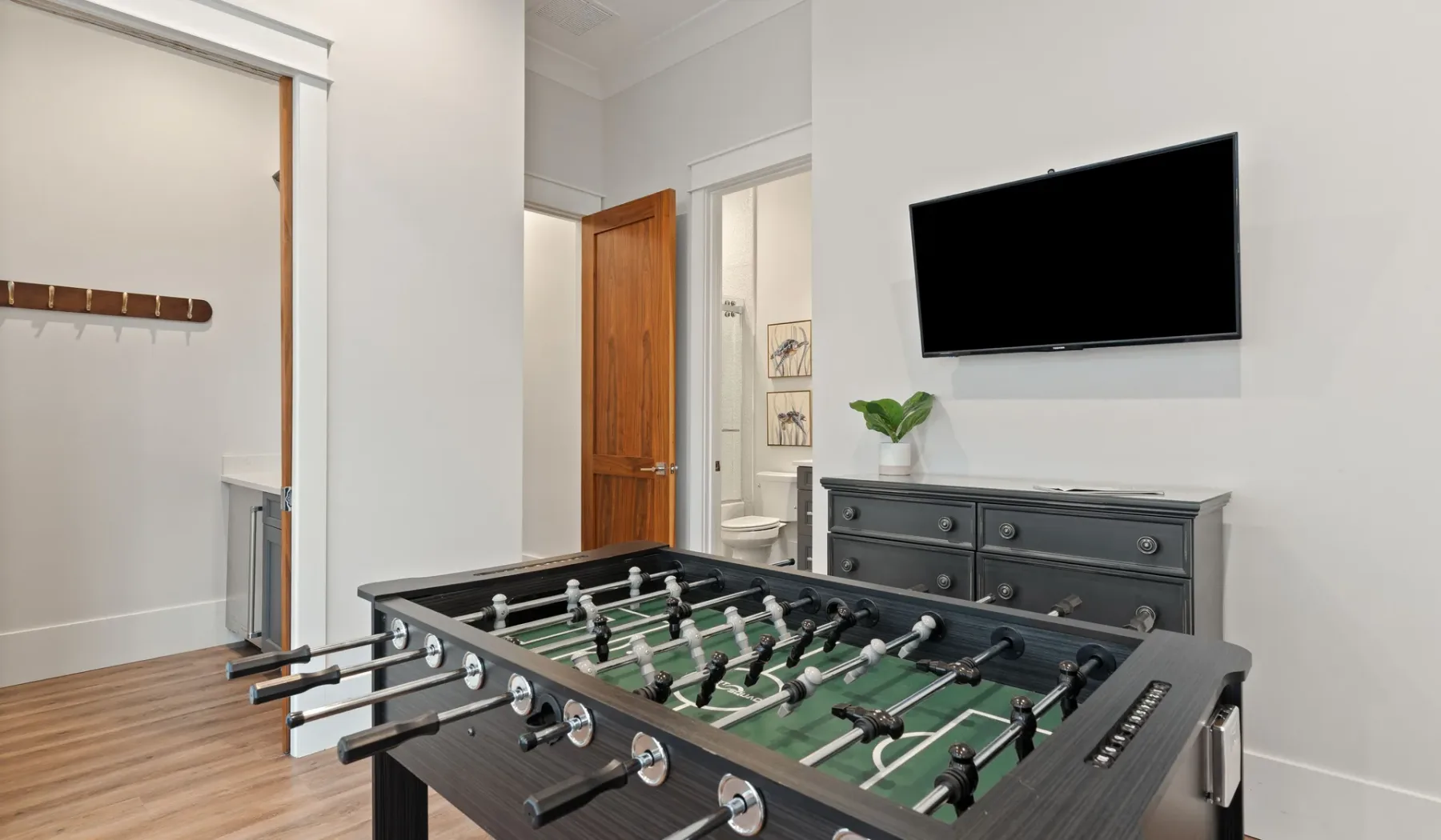 Una mesa de futbolín está en una habitación luminosa con un televisor montado en la pared.