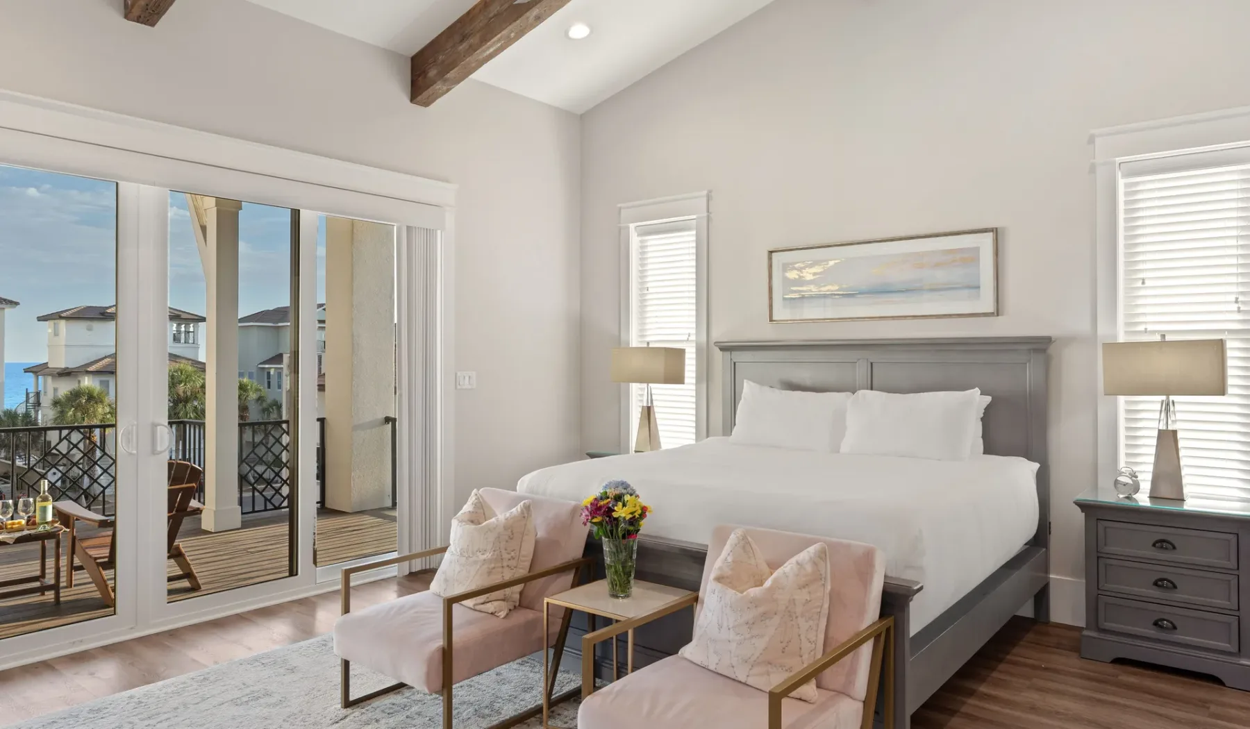 Un dormitorio luminoso con una cama grande, dos sillones y puertas corredizas de vidrio.
