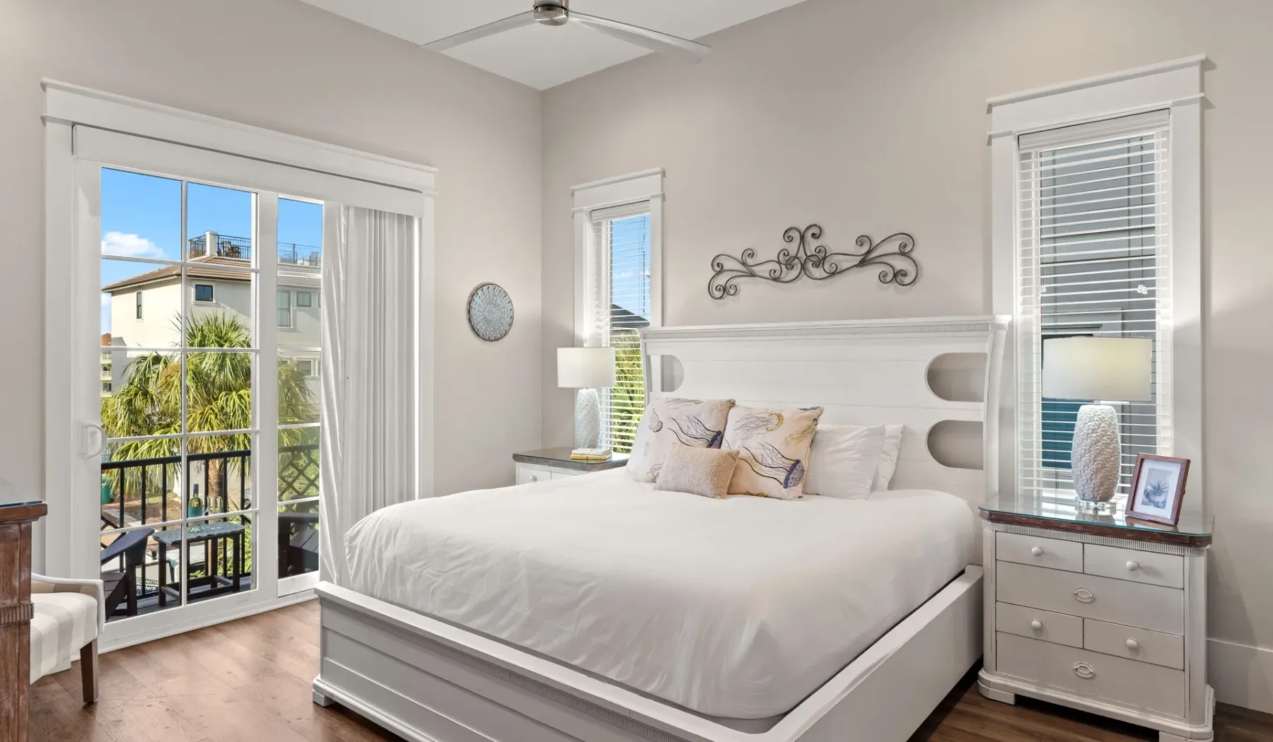 Un dormitorio luminoso con una cama bien tendida entre ventanas altas.