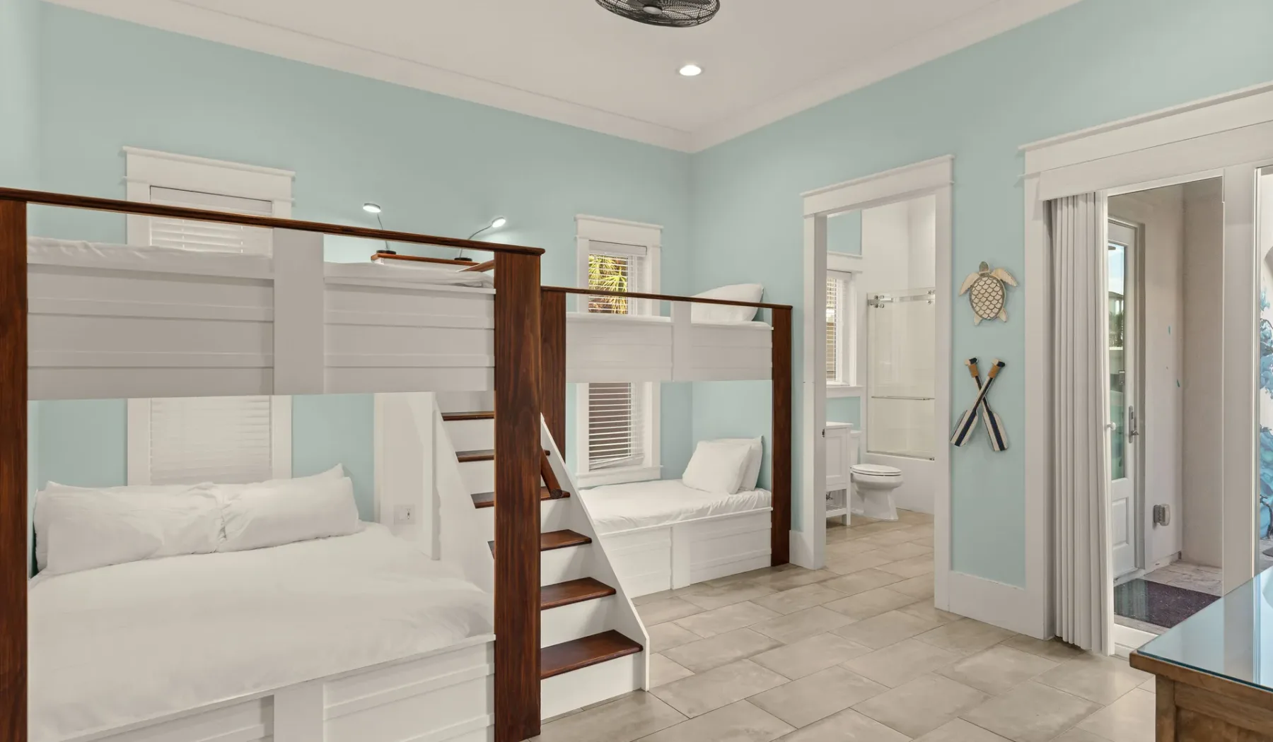 Un dormitorio con literas, ropa de cama blanca y suelo de baldosas.