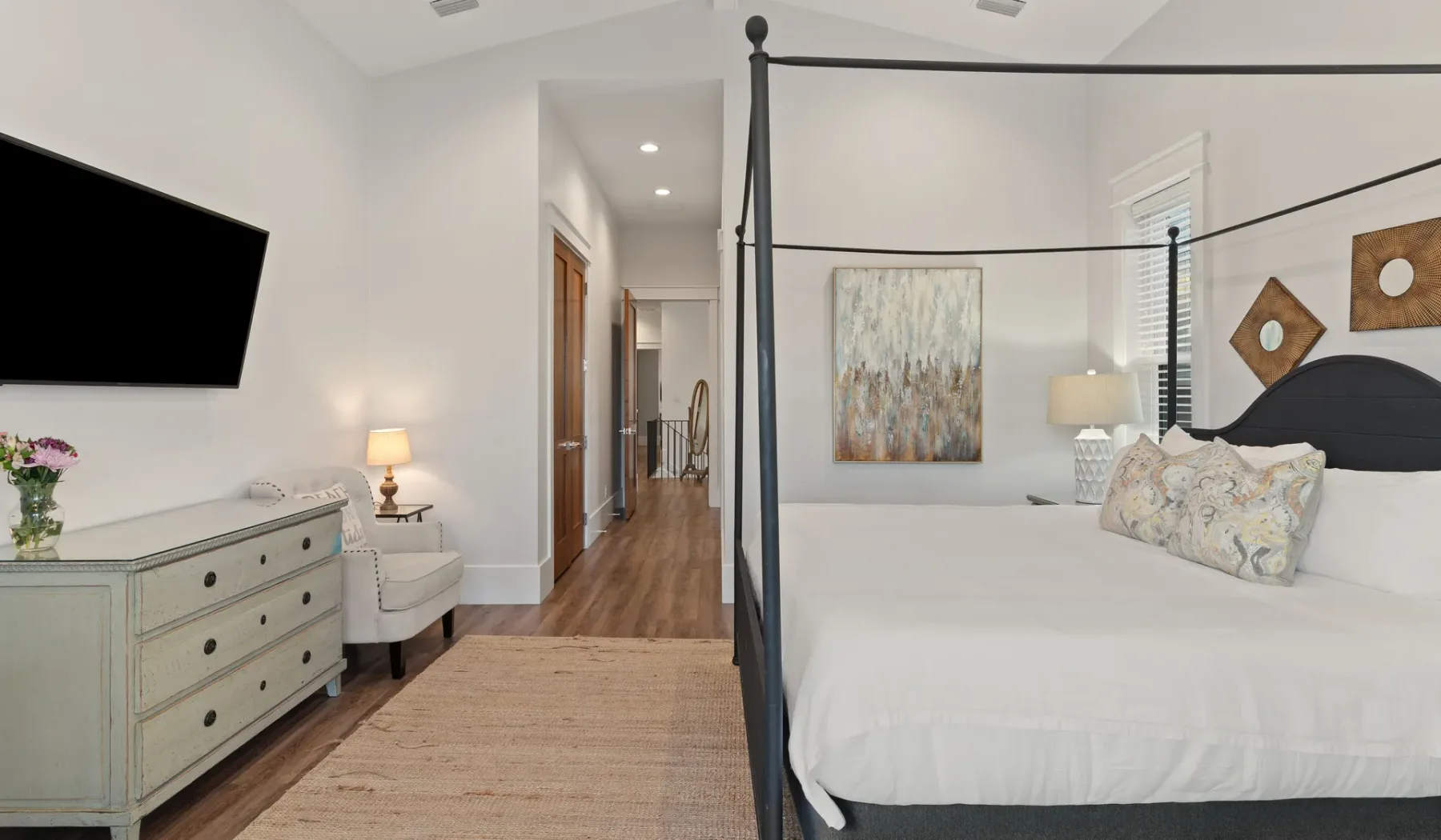 Un dormitorio con una cama grande, una cómoda y un pasillo al fondo.