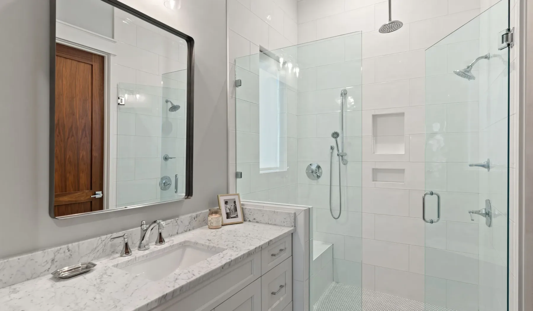 Un baño con azulejos, una ducha de vidrio y un tocador.