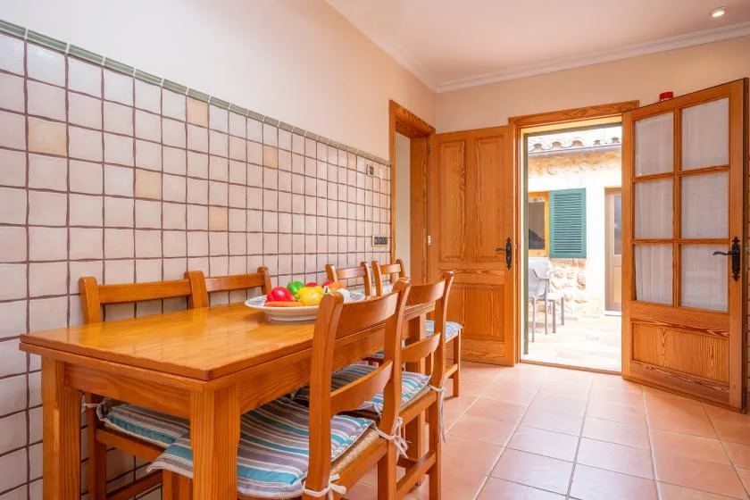 A dining area with a wooden table and chairs beside an open doorway.
