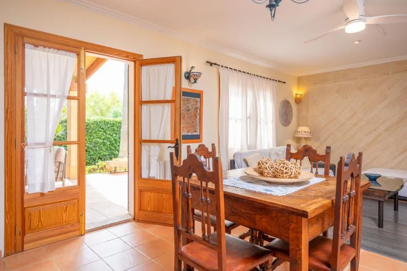 A dining room with a wooden table and chairs beside an open glass door.