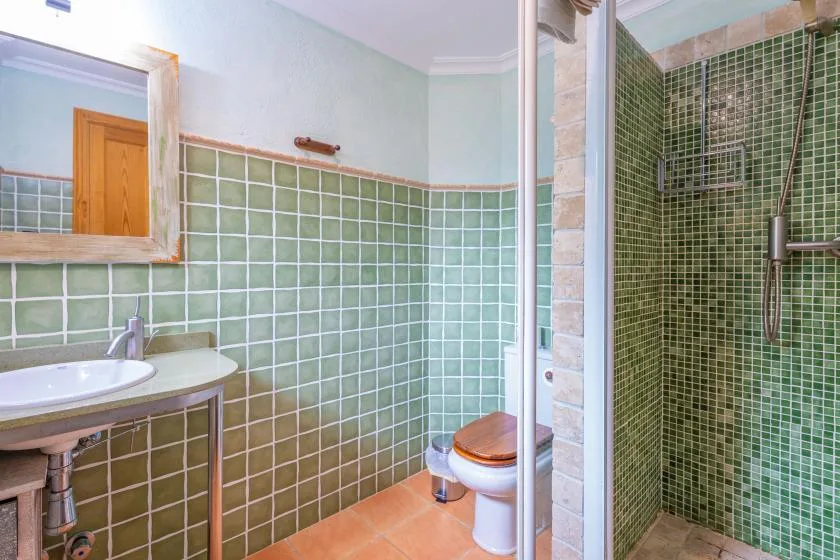 A tiled bathroom with a sink, toilet, and glass-enclosed shower.
