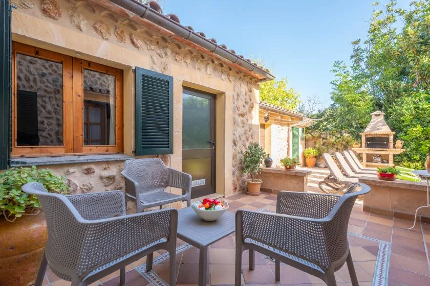 A tiled outdoor patio with seating, potted plants, and a built-in barbecue.