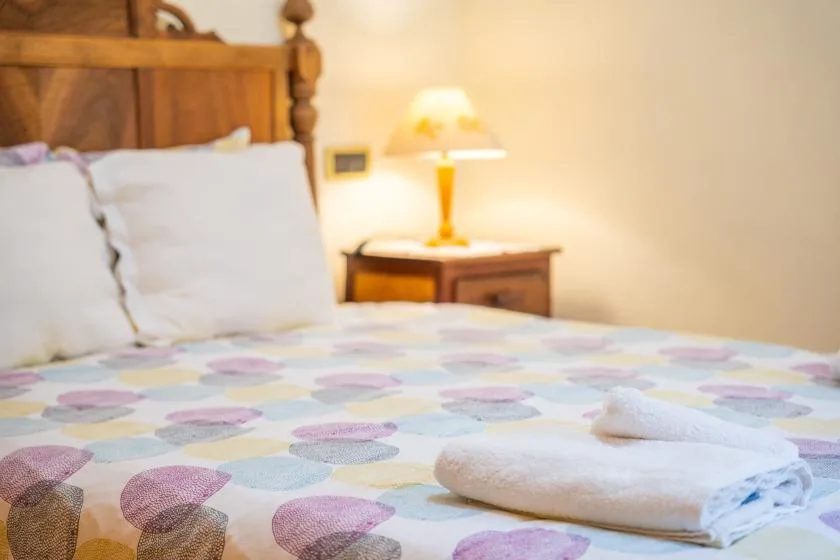 A bedroom with a wooden bed, patterned bedding, and a bedside lamp.