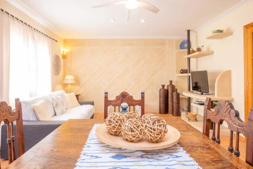 A bright living and dining area features a wooden table and seating beside a large window.