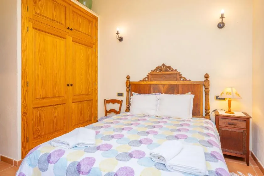 A bedroom with a wooden bed, patterned bedding, and a large wardrobe.
