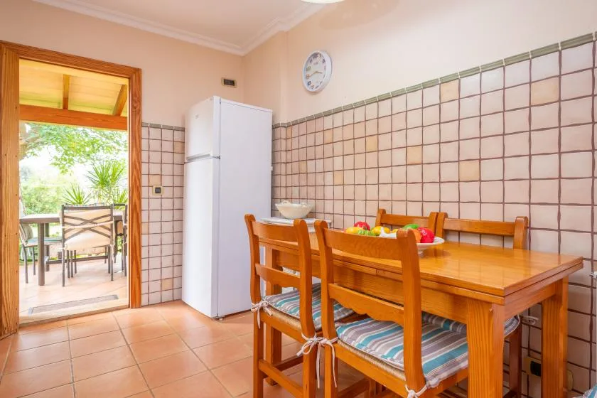 A dining area with a wooden table and chairs beside a refrigerator.
