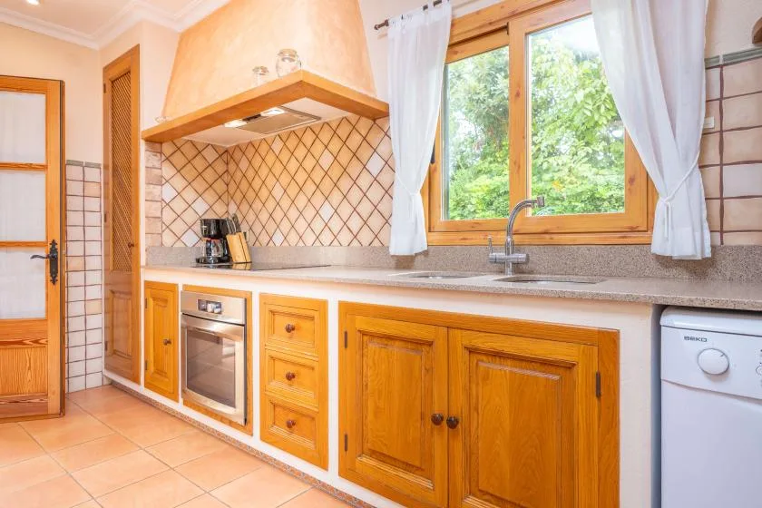 A bright kitchen with wooden cabinets, a countertop, and a window above the sink.