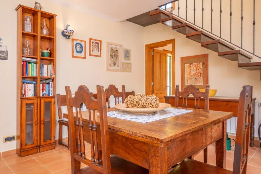 A dining room with a wooden table and chairs beneath a staircase.