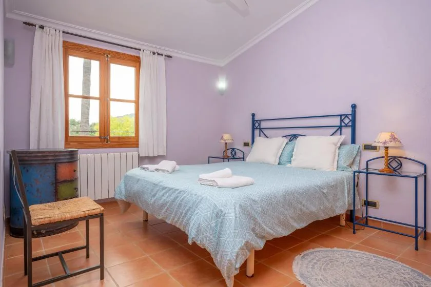A bedroom with a bed, pale walls, and a curtained window.