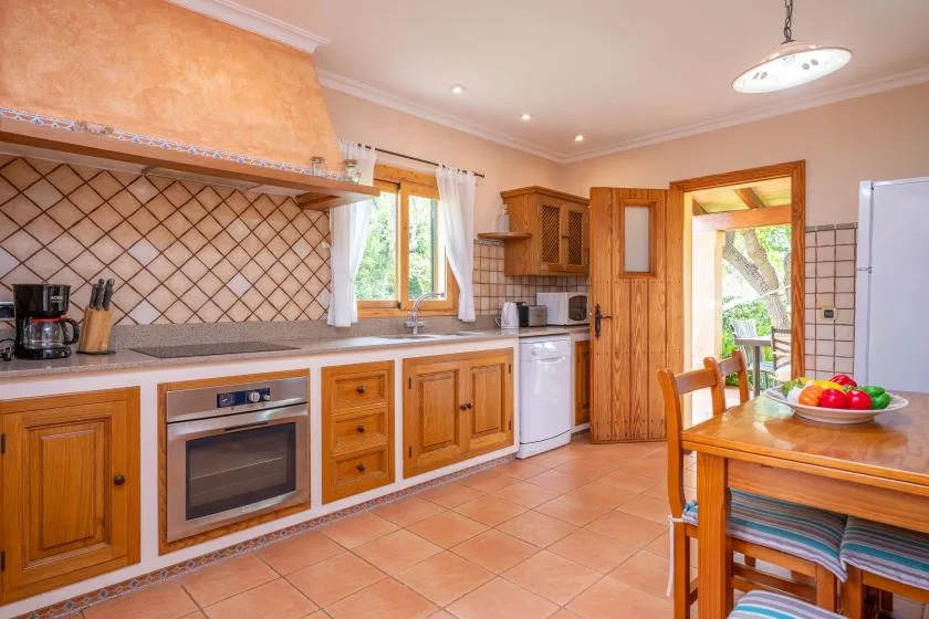 A warm-toned kitchen with wooden cabinets, a tiled backsplash, and a dining table.