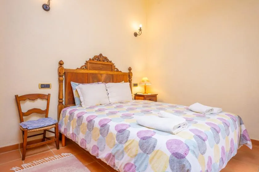 A bedroom with a double bed covered by a colorful patterned bedspread.
