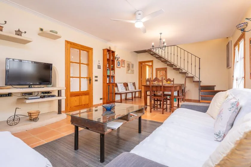 A living room with a dining table and staircase in the background.
