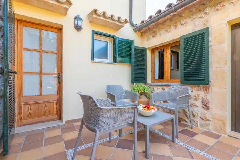 A tiled courtyard patio with outdoor seating beside a cream-colored building.