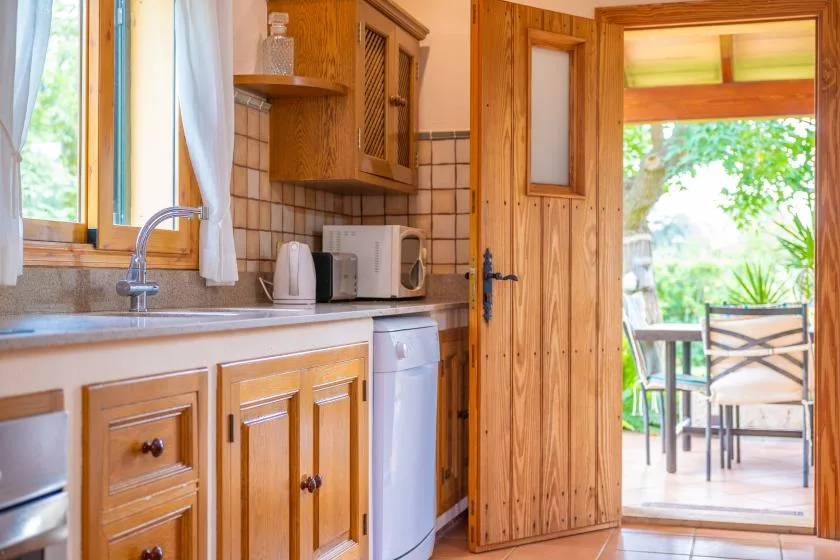 A wooden kitchen opens onto an outdoor patio with a table and seating.