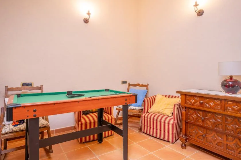 A game room with a pool table, striped seating, and a wooden dresser.