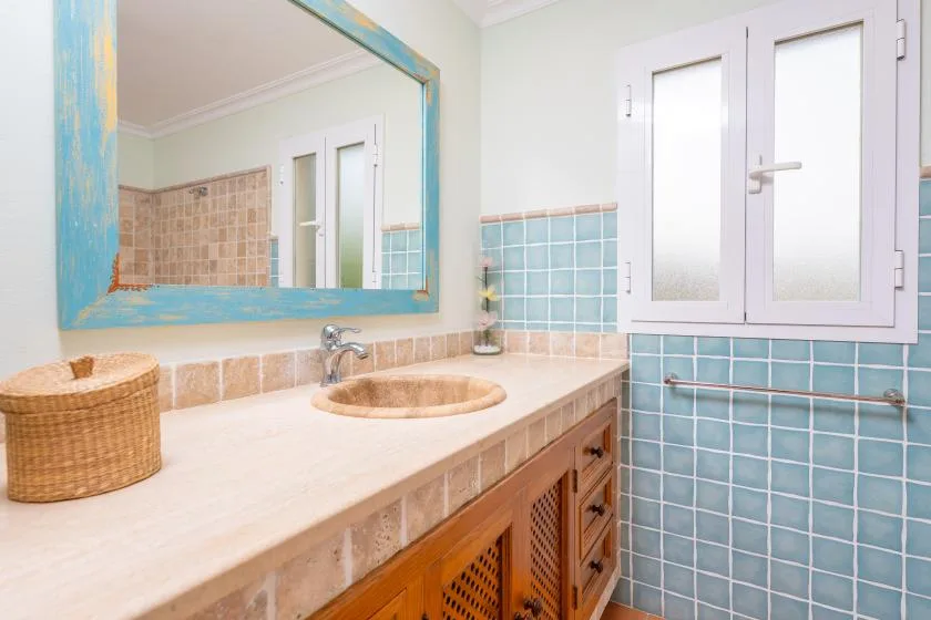 A tiled bathroom vanity with a round basin and a large wall mirror.