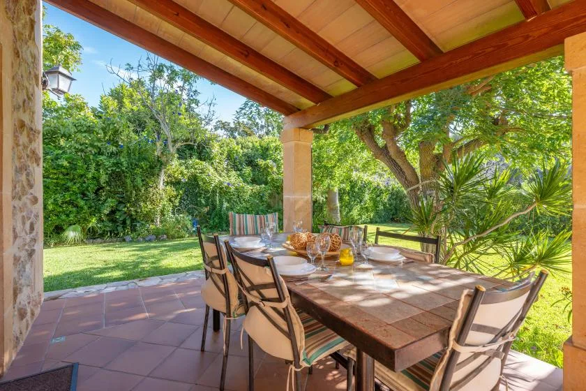 A covered outdoor dining area with a long table surrounded by seating.