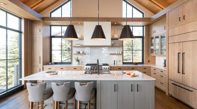 Una cocina espaciosa con una isla, lámparas colgantes y grandes ventanas.