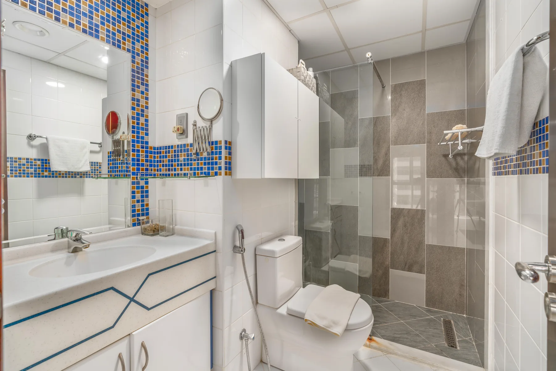 Un baño con lavabo y ducha con mampara de vidrio.
