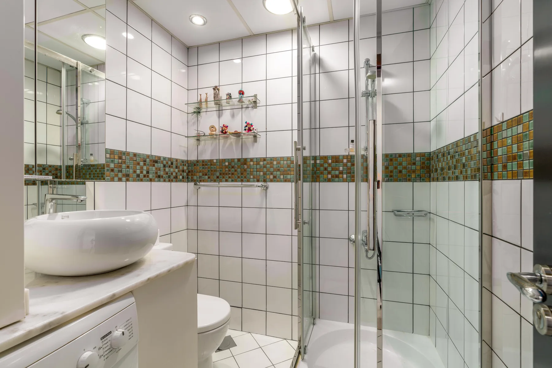 Un baño alicatado con ducha de vidrio y lavabo.