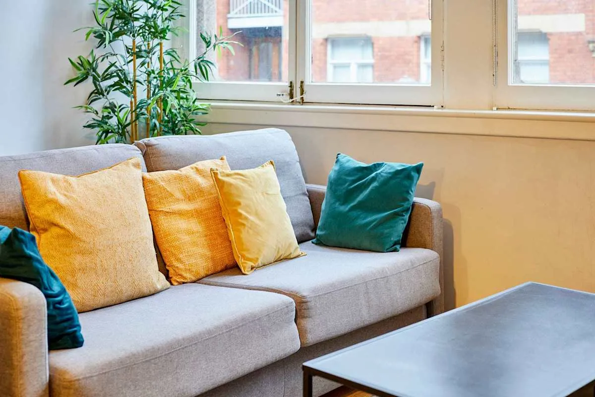 A living room with a gray sofa and colorful cushions beside a window.
