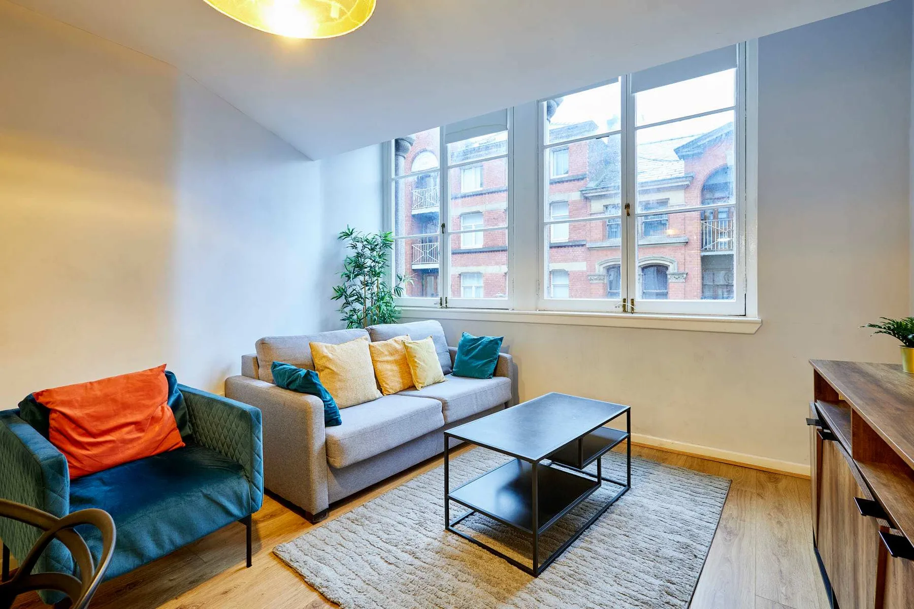 A bright living room with seating, a coffee table, and large windows.