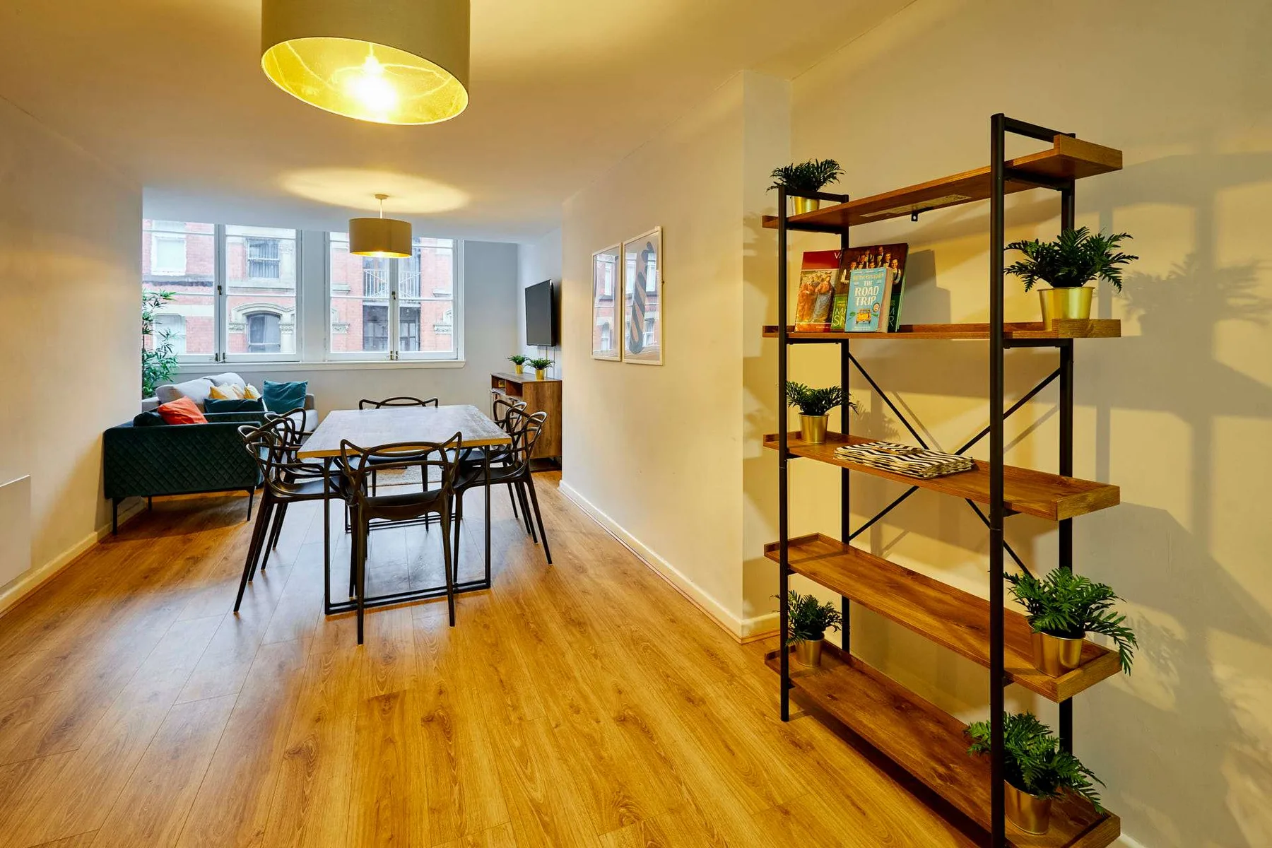 A dining area with a table and chairs sits beside a living area and open shelving.