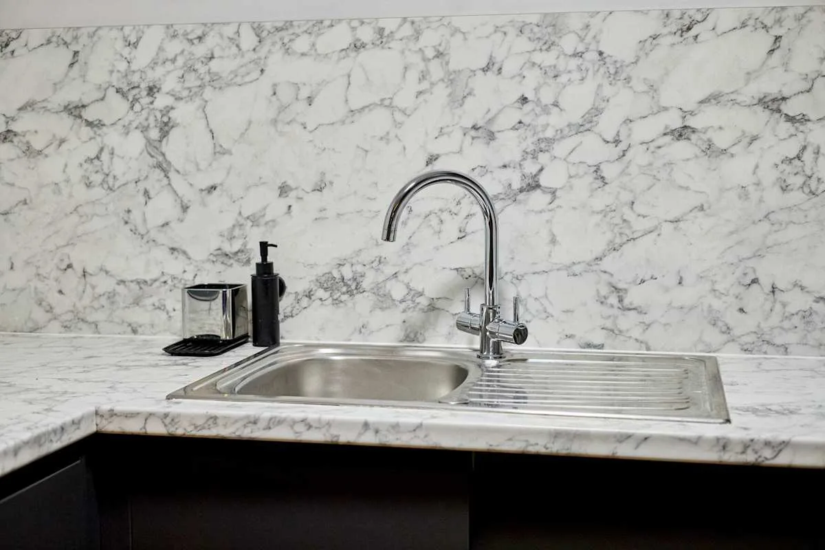 A kitchen sink with a curved faucet and draining board.