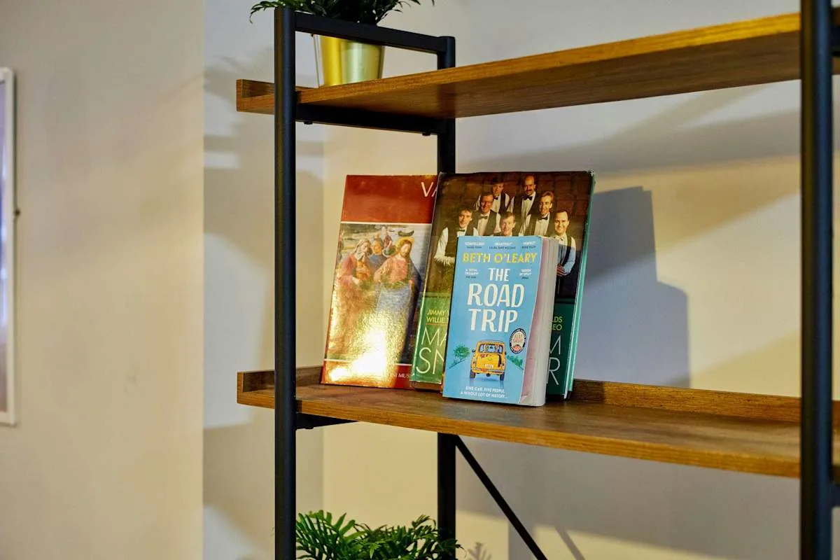 A shelving unit displays several books against a light-colored wall.