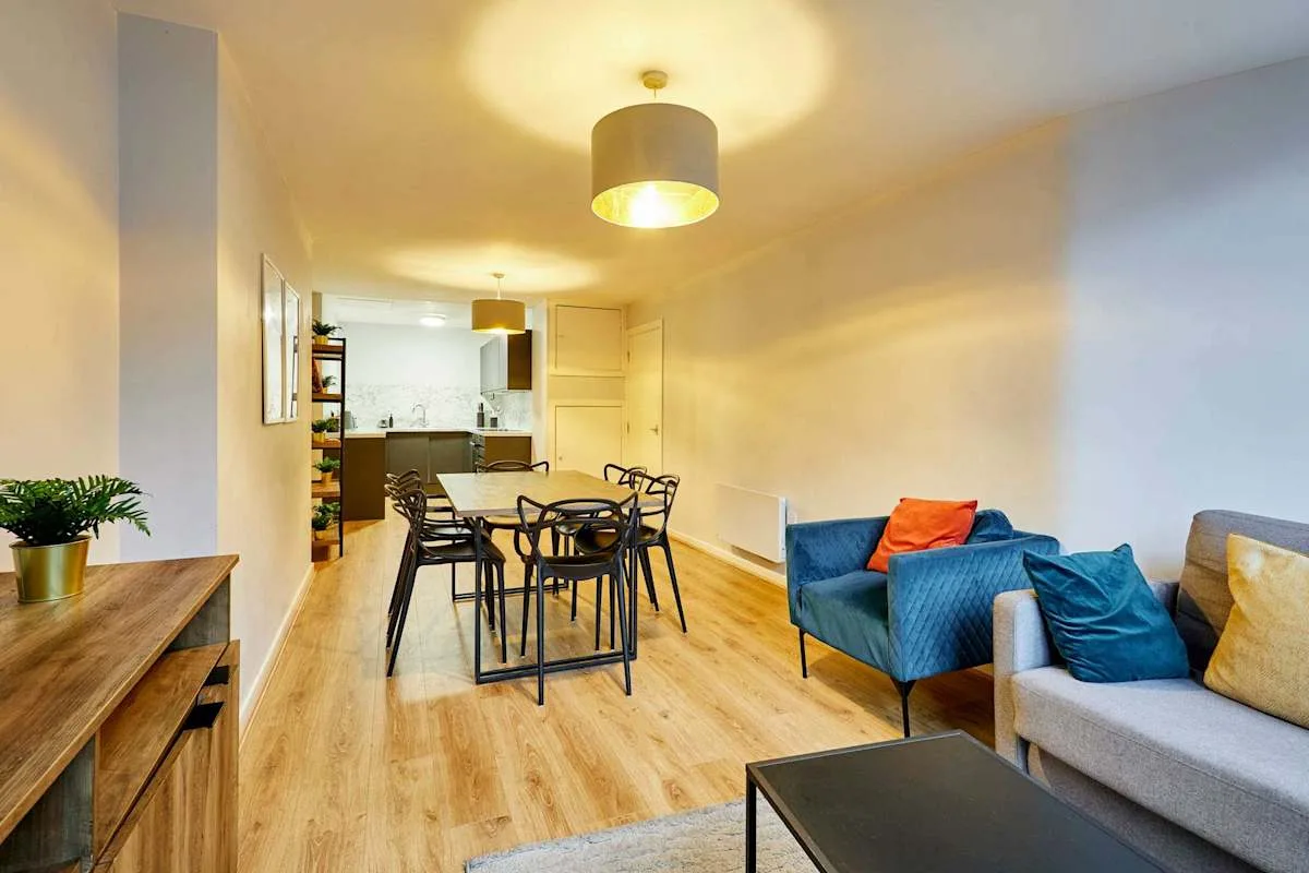 A living and dining area with a table, seating, and an open kitchen.
